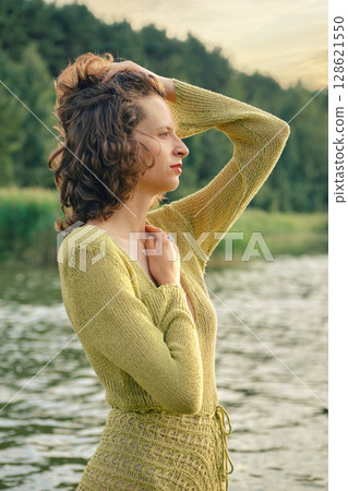 Warm summer afternoon by the lake with a woman enjoying nature Warm summer afternoon by the lake with a woman enjoying nature 128621550