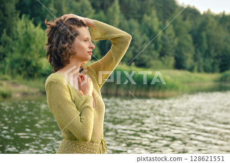 Warm summer day by the lake with a woman enjoying the serene waterside view Warm summer day by the lake with a woman enjoying the serene waterside view 128621551