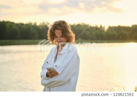 Enjoying a warm day at the lake while checking messages on a smartphone 128621561