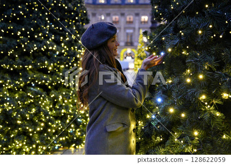 Woman touching glowing Christmas lights in Paris Woman touching glowing Christmas lights in Paris 128622059