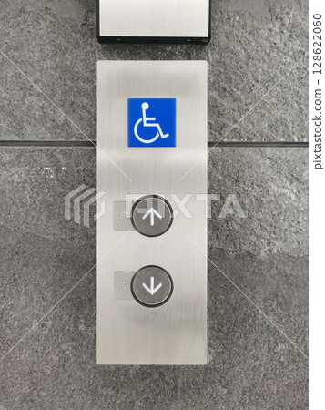 Up/down elevator buttons and wheelchair symbols on the cement wall. Up/down elevator buttons and wheelchair symbols on the cement wall. 128622060