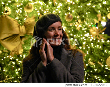 Woman posing near illuminated tree with golden bow at night Woman posing near illuminated tree with golden bow at night 128622062