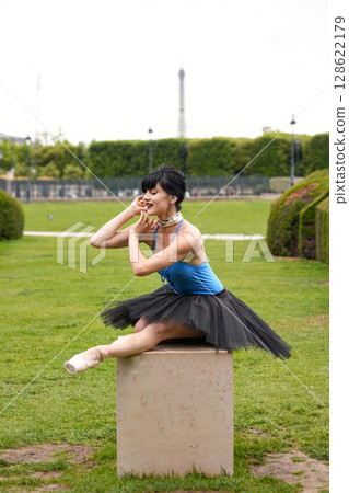 Ballet dancer sitting on pedestal in outdoor park setting 128622179