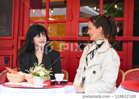 Women talking over coffee at a red Parisian cafe 128622189