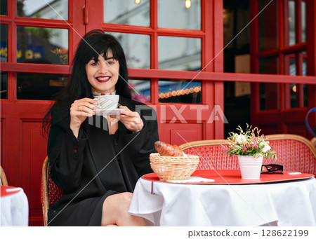 Smiling woman holding coffee at a Paris street cafe Smiling woman holding coffee at a Paris street cafe 128622199