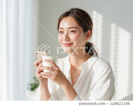 Relaxed woman looking at her smartphone in the morning light 128622286