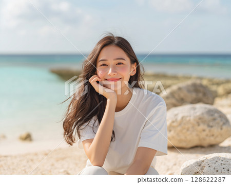 Photo of a woman laughing on a beach with blue sky and ocean 128622287
