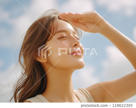 A young woman is looking up at the sky under clear skies with her hands A young woman is looking up at the sky under clear skies with her hands 128622305