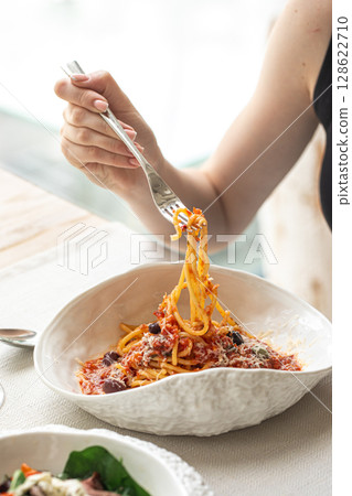 Woman twirling spaghetti with tomato and olives Woman twirling spaghetti with tomato and olives 128622710