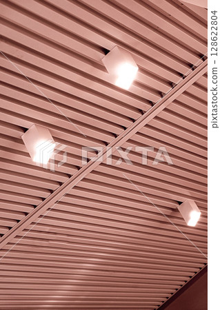 Ceiling with bright lights in a modern warehouse, shopping center building, office or commercial real estate object. Directional LED lights on rails under the ceiling 128622804