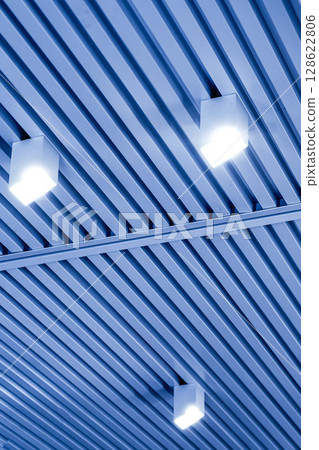 Ceiling with bright lights in a modern warehouse, shopping center building, office or commercial real estate object. Directional LED lights on rails under the ceiling 128622806