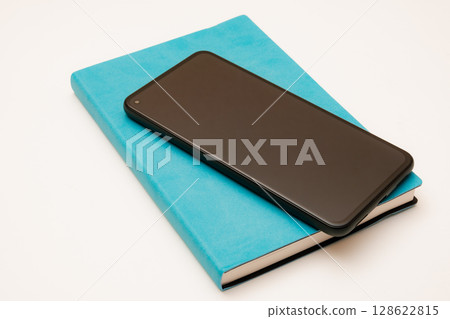 A simple composition of a smartphone and a blue notebook 128622815