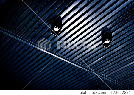 Bottom view of lath ceiling with spot lights. Abstract modern architecture or interior background in black and white with geometric structure. 128622855