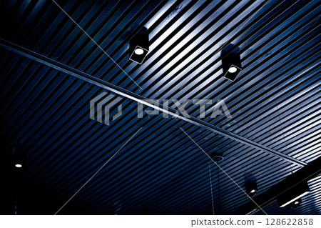 Bottom view of lath ceiling with spot lights. Abstract modern architecture or interior background in black and white with geometric structure. Bottom view of lath ceiling with spot lights. Abstract modern architecture or interior background in black and white with geometric structure. 128622858