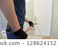 With a roller, apply paint to the surface, paint the walls in the apartment, does repairs with white paint. With the ability to copy. High quality photo 128624152