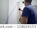 A man paints concrete walls with a paint roller. Gray paint creates a cozy atmosphere in the room. High quality photo 128624153