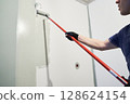 A worker paints the inner wall of his house. Apartment renovation. Concrete walls are painted gray with a paint roller. High quality photo 128624154