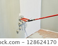 Insulated wires are sticking out of the wall. Close-up of a roller painting a wall in the color of hakka. Apartment painting, renovation. There is a place to copy. High quality photo 128624170