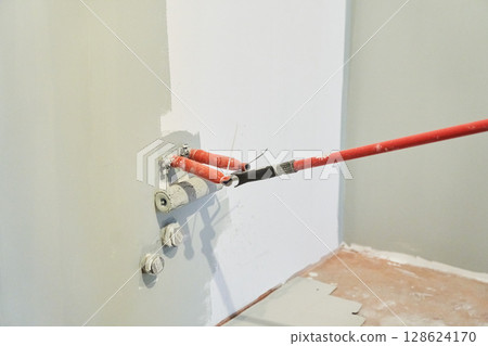 Insulated wires are sticking out of the wall. Close-up of a roller painting a wall in the color of hakka. Apartment painting, renovation. There is a place to copy. High quality photo 128624170