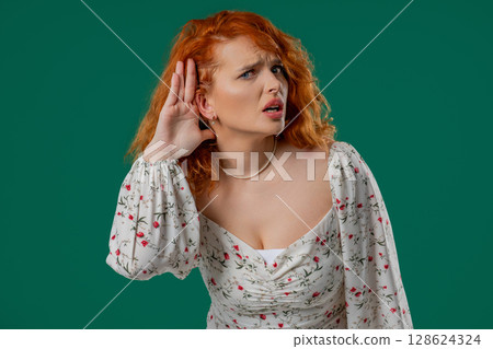 Ginger woman pointing to ear with confused face, signaling she cant hear clearly Ginger woman pointing to ear with confused face, signaling she cant hear clearly 128624324