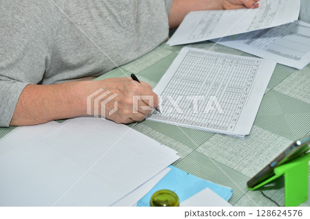 A woman works with documents while sitting at a table. A woman works with documents while sitting at a table. 128624576