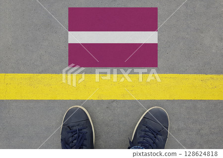 Start on an asphalt road with the Latvian flag and legs in shoes. Business, Immigration and Travel  128624818
