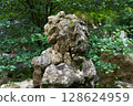 Natural Moss-Covered Rock Formation in a Lush Forest Garden with Serene Green Foliage Background 128624959