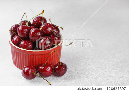 Red bowl full of fresh organic sweet cherries on white stone background, healthy summer snack Red bowl full of fresh organic sweet cherries on white stone background, healthy summer snack 128625897
