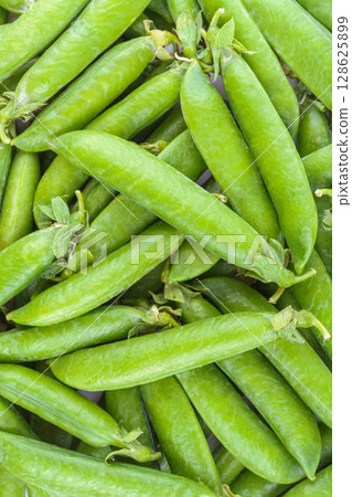 Fresh green pea pods arranged in a natural organic pattern, close up top view, food background Fresh green pea pods arranged in a natural organic pattern, close up top view, food background 128625899