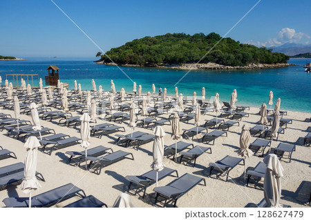 beach umbrellas closed during low season on the beach in Ksamil, Albanian rivieira 128627479