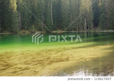 sunset reflects over green surface of Zminje lake in Durmitor National Park, Zabljak, Montenegro 128627607
