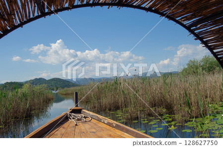 wooden raft sails among lilies in Lake Skadar, on the border of Albania and Montenegro 128627750