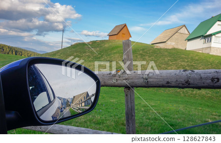 country cottages on top of green field and image reflected in the car rearview mirror country cottages on top of green field and image reflected in the car rearview mirror 128627843