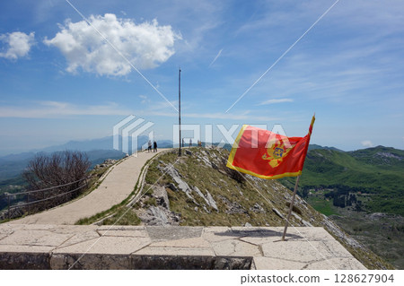 Montenegrin flag hoisted on top of Mount Lovcen at entrance of Mausoleum of Njegos. Cetinje, Montenegro Montenegrin flag hoisted on top of Mount Lovcen at entrance of Mausoleum of Njegos. Cetinje, Montenegro 128627904