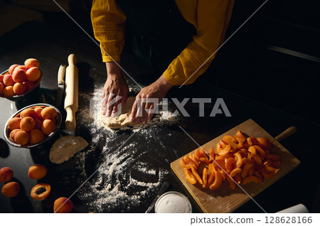 Hands Preparing Dough Surrounded by Fresh Apricots in a Cozy Kitchen 128628166