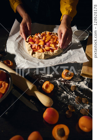 Woman Preparing Apricot Tart in Rustic Kitchen Setting for Baking Woman Preparing Apricot Tart in Rustic Kitchen Setting for Baking 128628178