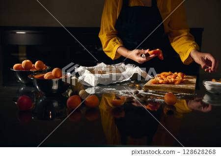Woman Prepares Fresh Apricots in a Kitchen Setting with Warm Mood Lighting Woman Prepares Fresh Apricots in a Kitchen Setting with Warm Mood Lighting 128628268