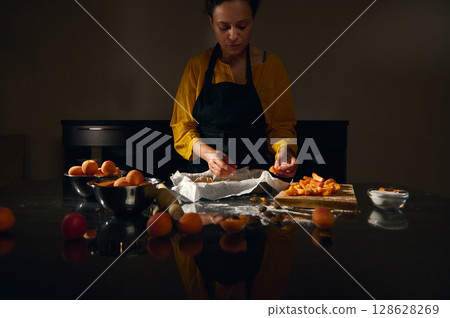 Woman Chef Preparing Fresh Apricot Pastry in a Rustic Kitchen Setting 128628269