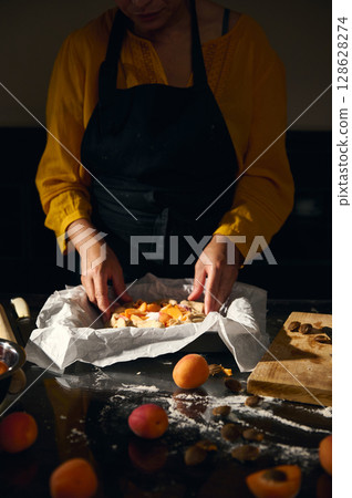 Woman Preparing Homemade Fruit Pastry with Apricots in a Rustic Kitchen 128628274