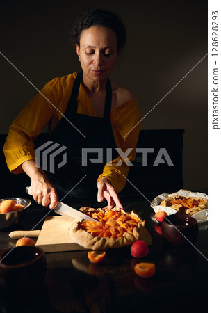 Chef Preparing a Rustic Apricot Tart in a Warmly Lit Kitchen Setting Chef Preparing a Rustic Apricot Tart in a Warmly Lit Kitchen Setting 128628293