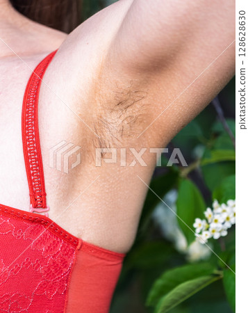 Closeup of long dark hair growing under arm of young female. Concept of hygiene, natural beauty, feminity and body hair growth 128628630