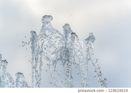 Splashes and jets of water against light background. Splashes and jets of water against light background. 128628810