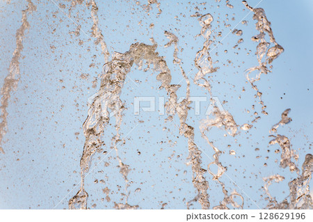 Splashes and jets of water against light background. 128629196