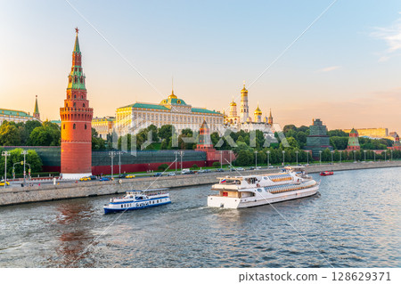 View of Kremlin with Vodovzvodnaya tower, Grand Kremlin Palace from repaired Bolshoy Kamenny Bridge in Moscow city on sunny summer day. Cruise ship sails on the Moscow river 128629371