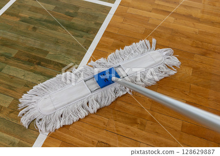 Cleaning Mop on Wooden Floor with Court Lines in Gymnasium or Sports Hall. 128629887