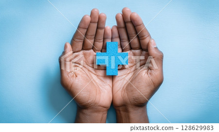 Hands holding a blue medical cross, symbolizing care, health, and protection against illness. Focus on wellness, insurance, and compassion. 128629983
