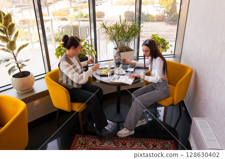 Entrepreneurs discuss project execution while having lunch. Concept of remote work, leadership, and business clarity. Top view, wide shot 128630402