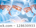 Medical team of surgeons performing a delicate operation in a bright, sterile environment 128630933