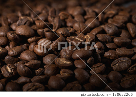Roasted coffee bean dropping against a blurred coffee bean background Roasted coffee bean dropping against a blurred coffee bean background 128632266