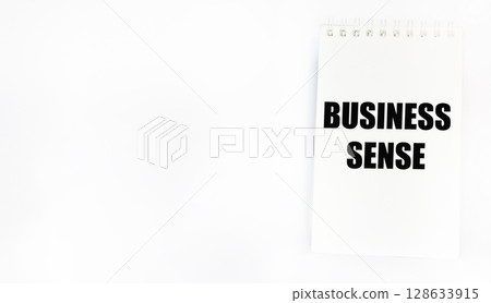 A symbol of business sense. Conceptual words business sense on a notebook. White background, 128633915